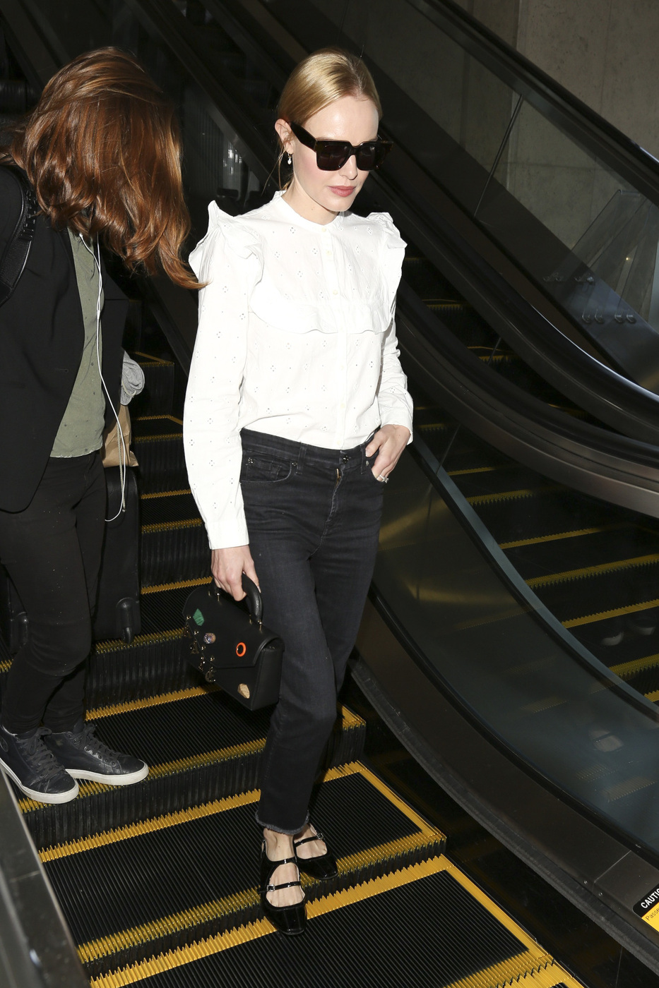 Kate Bosworth wears a white ruffle shirt with black jeans and black Mary Jane flats.