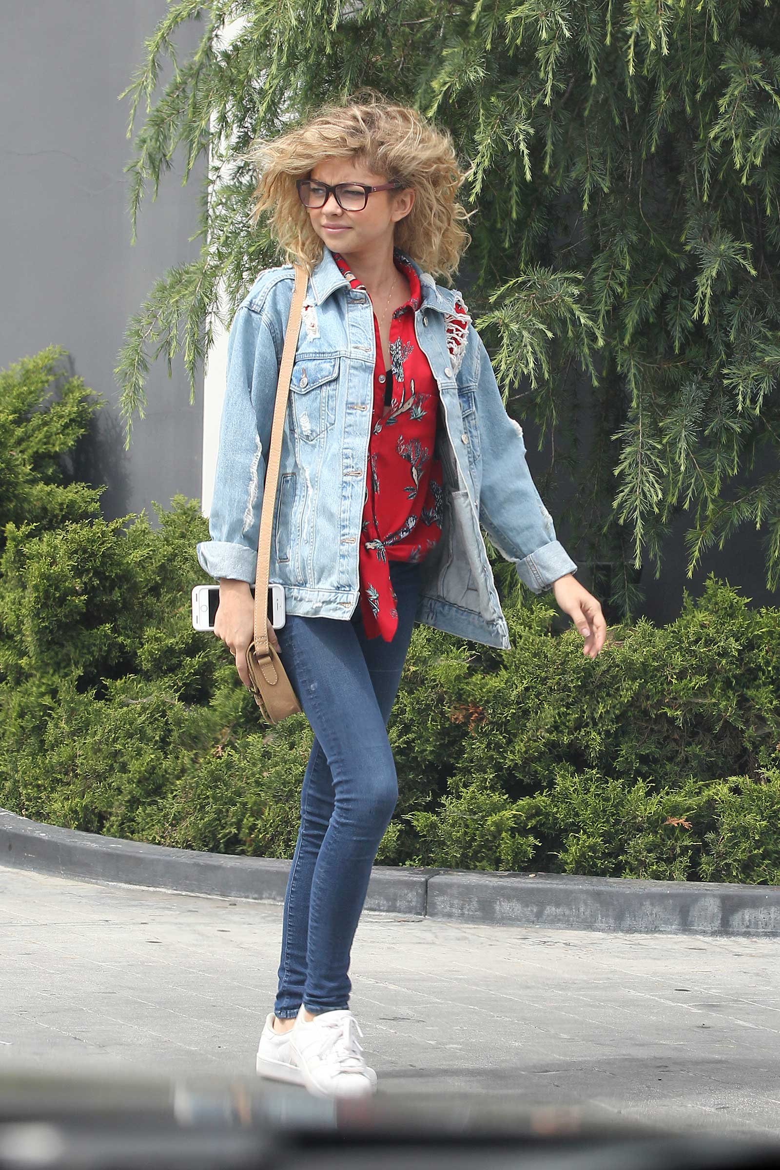 Sarah Hyland is cute and casual in a jean jacket, red print shirt and white sneakers.
