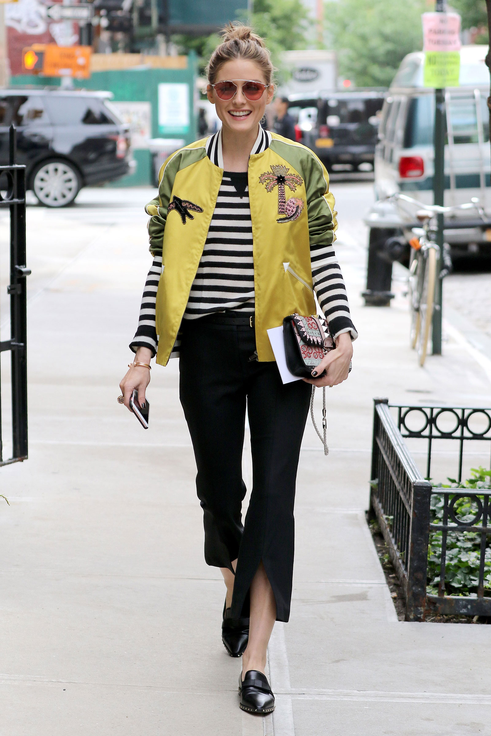 Olivia Palermo wears a yellow satin applique bomber jacket by Valentino with flare cuff pants.
