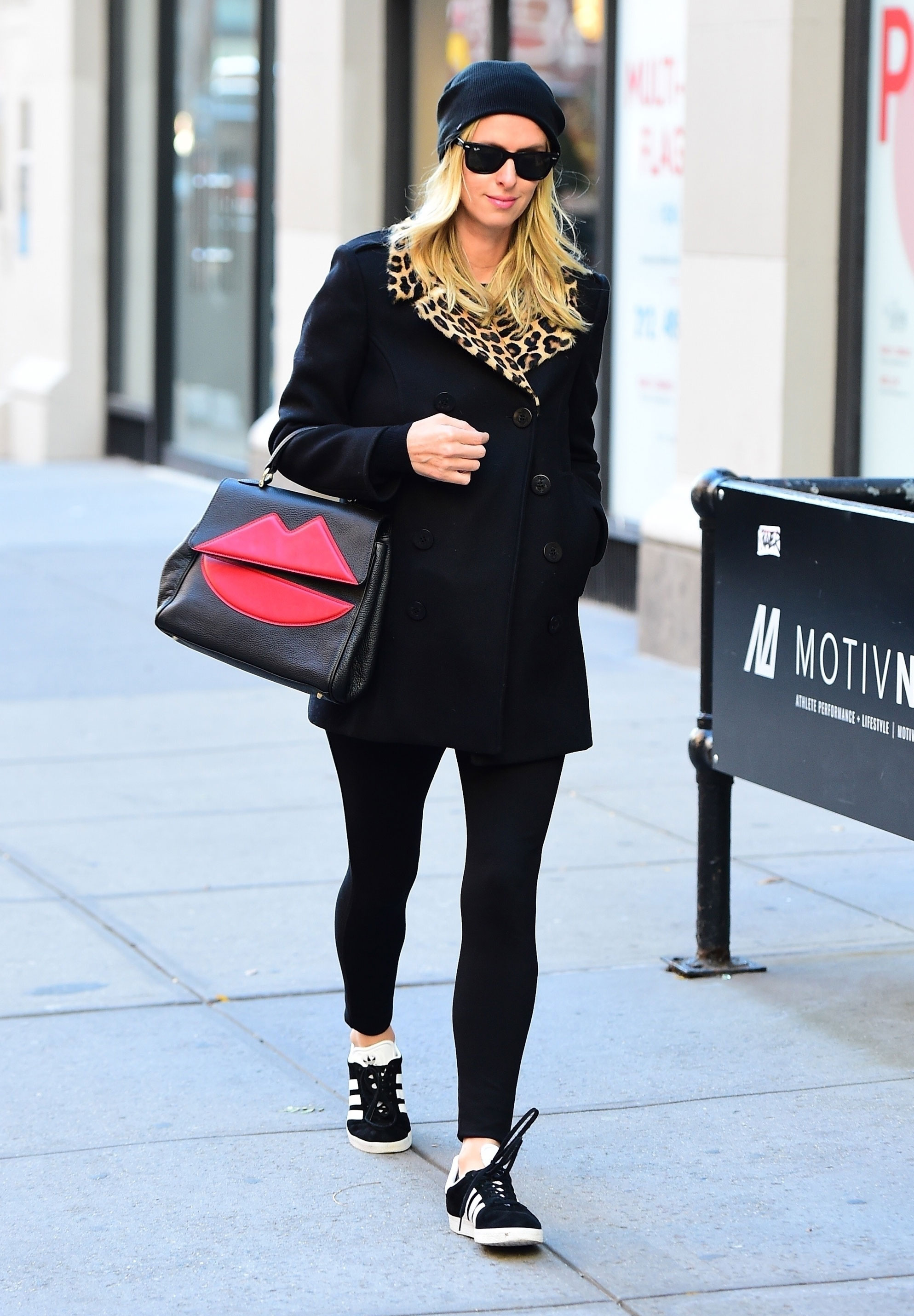 Nicky Hilton wears a black wool coat with leopard faux fur collar and red 'lips' bag by Sara Battaglia.