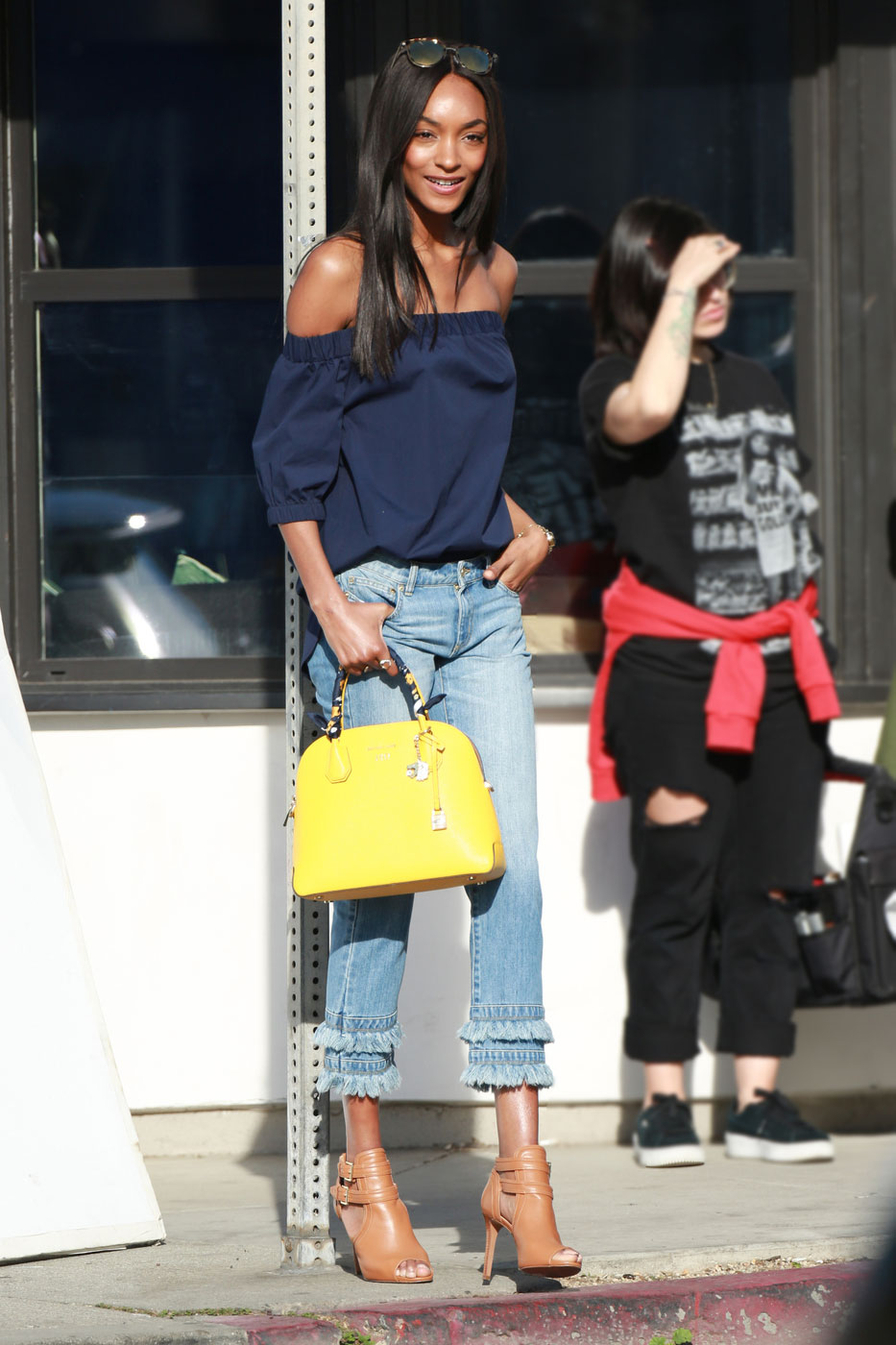 Jourdan Dunn pairs a navy off-the-shoulder top with fringe jeans and a yellow satchel.