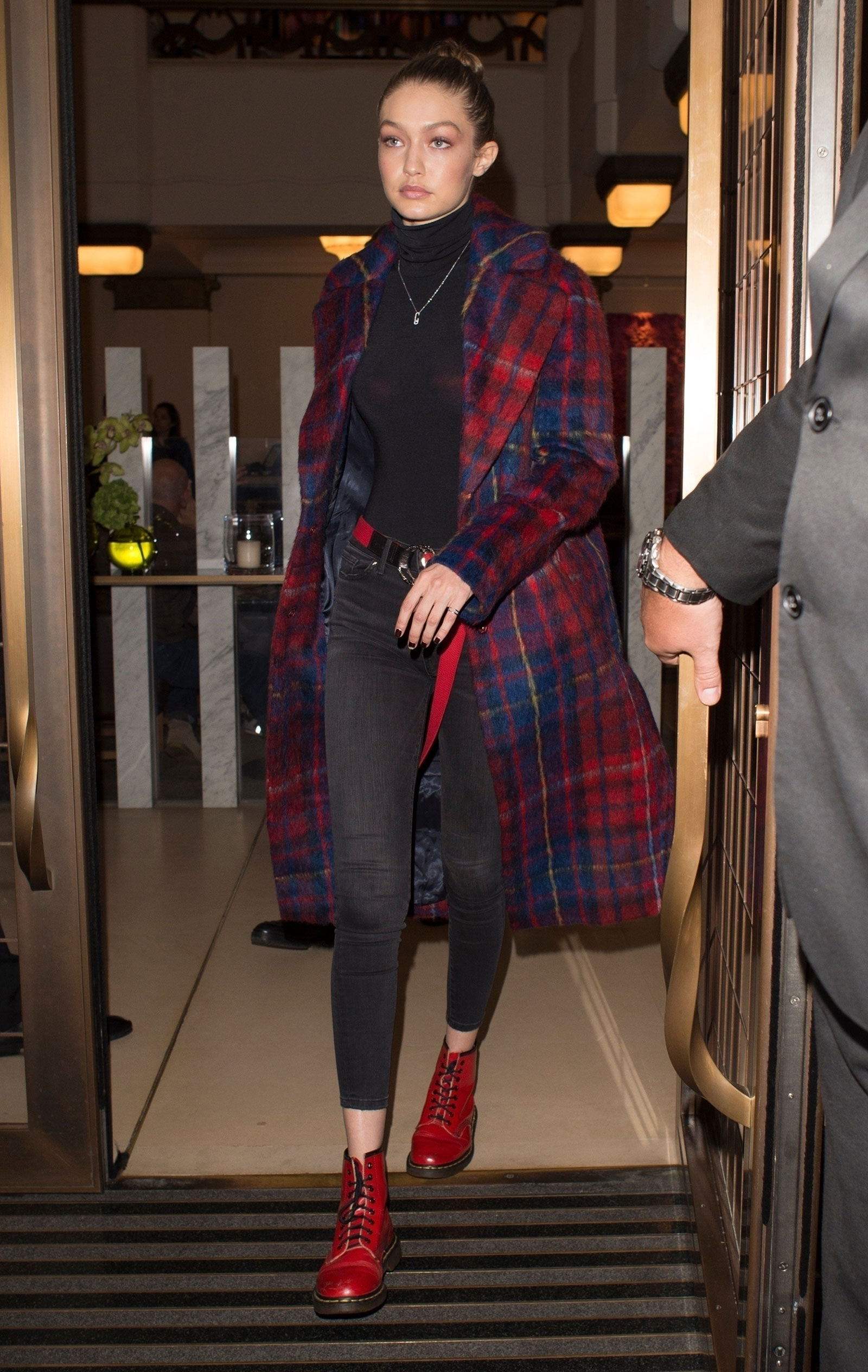 Gigi Hadid steps out in a plaid coat, black turtleneck and red combat boots.