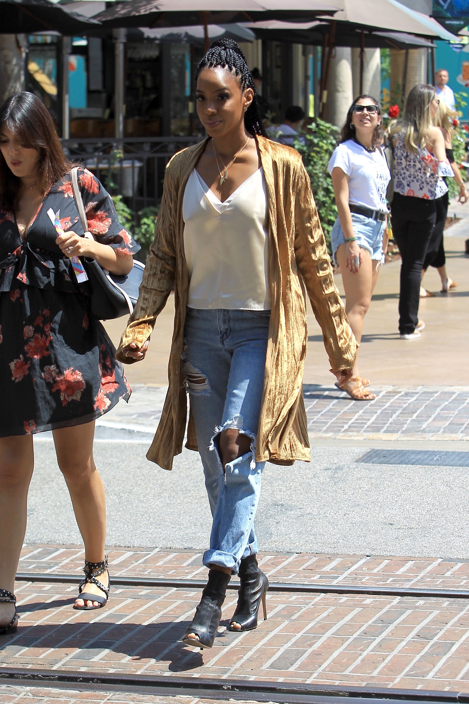 Kelly Rowland wears a gold mustard yellow velour duster with destroyed denim and black peep-toe ankle booties.