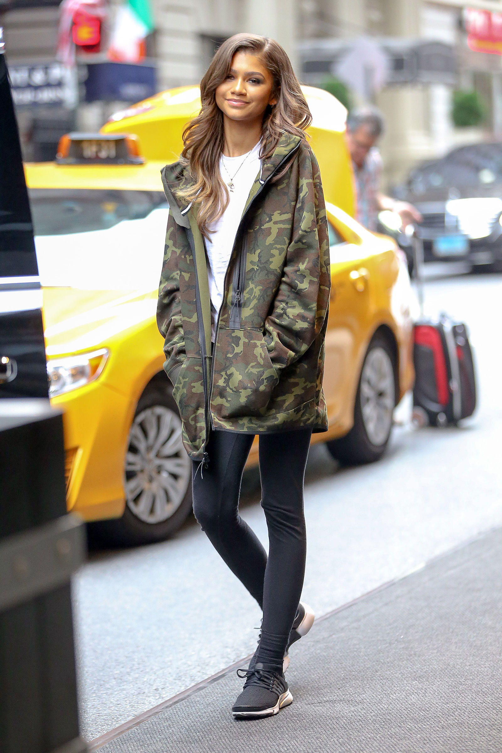 Zendaya styles her camo jacket with leggings, sneakers and soft curls.