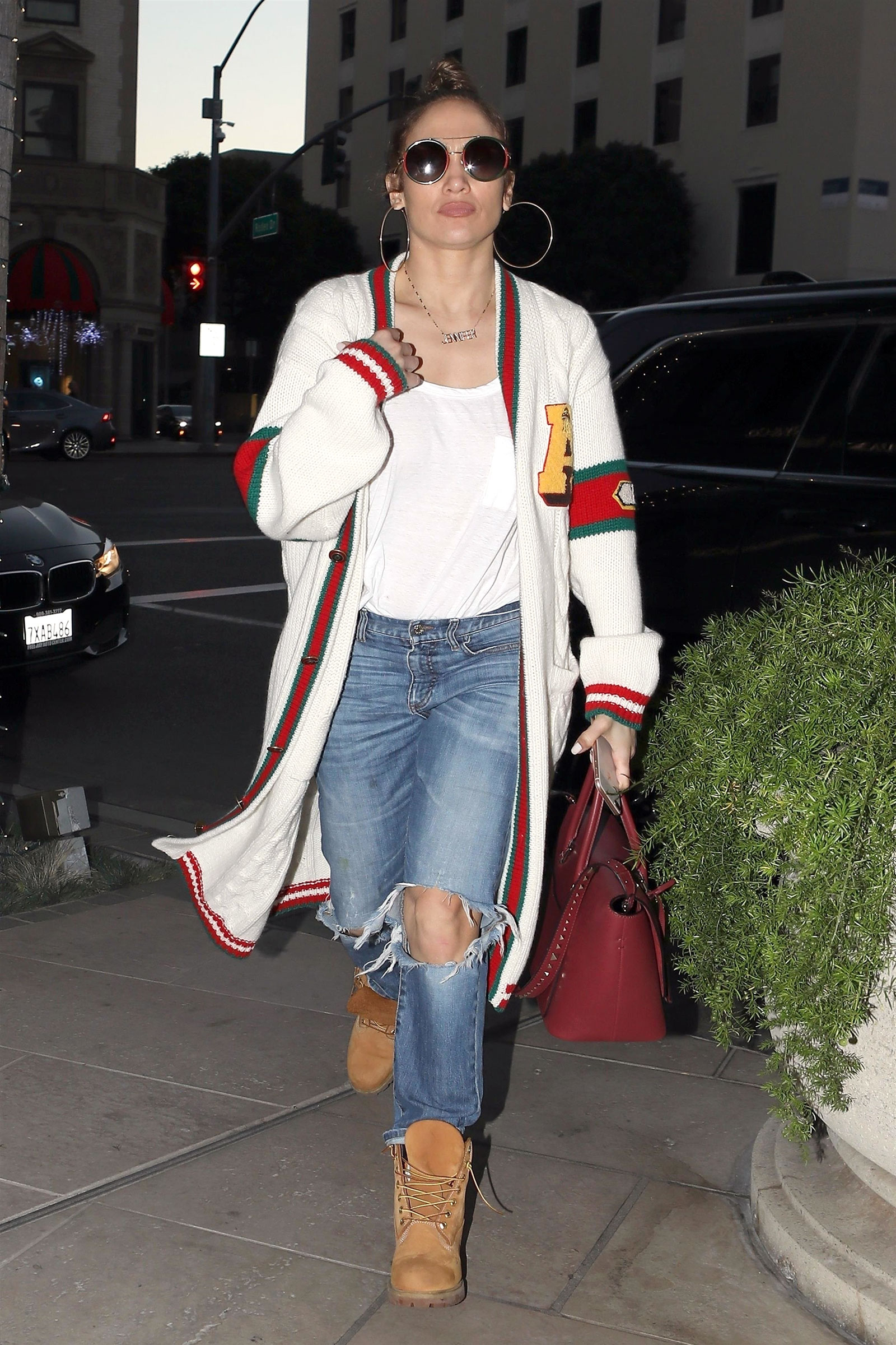 Jennifer Lopez wears a Gucci cardigan sweater with ripped jeans, Timberland boots and Valentino trapeze bag.