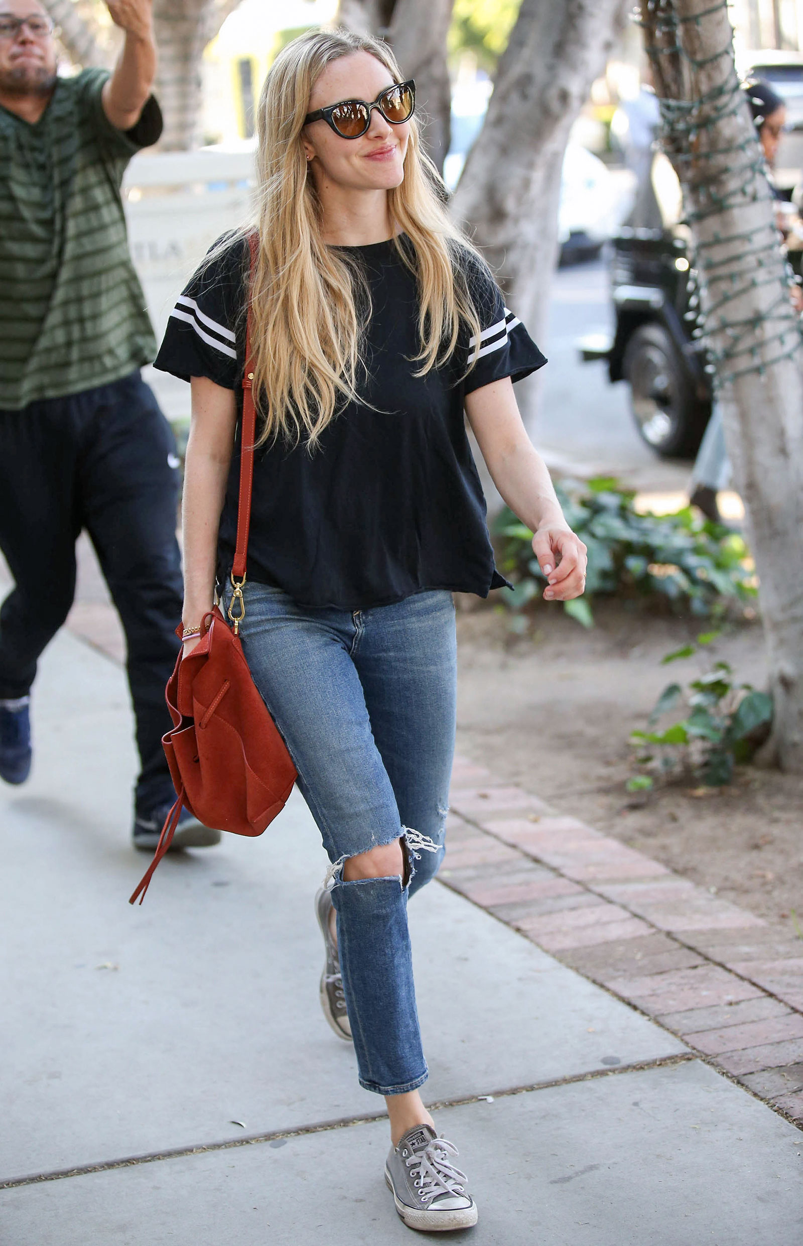 Amanda Seyfriend looks cute and sporty in a varsity stripe tee, ripped jeans and Converse Chuck Taylor All Star sneakers.