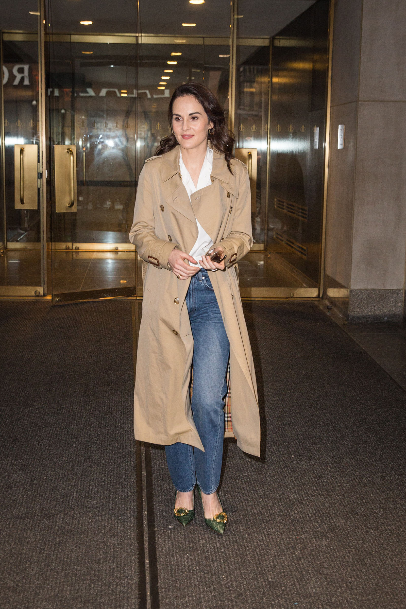 Michelle Dockery looks classic and chic in a trench coat, jeans, and green flats!